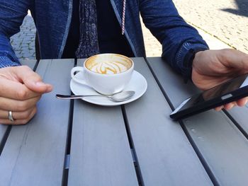 Low section of woman holding coffee cup on table