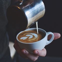 Midsection of person pouring coffee in cup