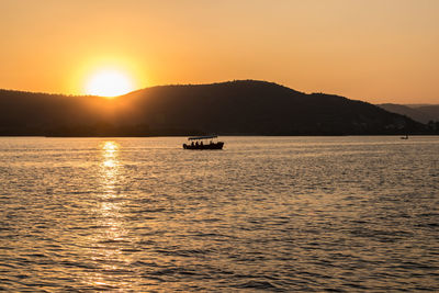 Silhouette boat sailing on sea against sky during sunset