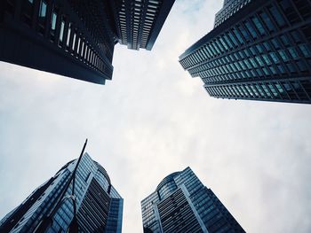 Low angle view of skyscrapers against cloudy sky