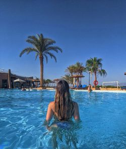 Rear view of woman with palm trees in swimming pool
