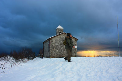 Man on snow covered field against sky during winter