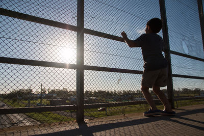 Little boy looking through fence