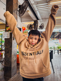 Portrait of young man standing with both arms raised 