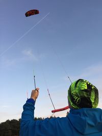 Low angle view of man holding parachute against sky