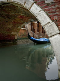 Gondola moored on grand canal seen through arch bridge