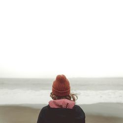 Rear view of woman wearing knit hat against sea at beach