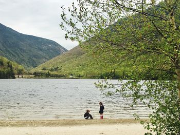 People on lake against mountain