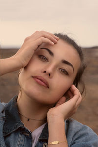 Close-up portrait of a beautiful young woman against sky