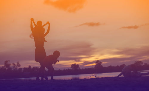 Silhouette people on beach against sky during sunset