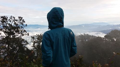 Rear view of man looking at mountains against sky