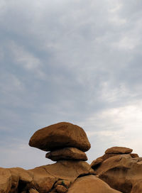 Low angle view of rock formation against cloudy sky