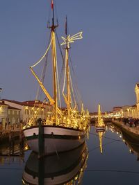 Sailboats moored in city against clear sky