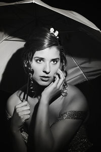 Close-up of young woman with umbrella in darkroom