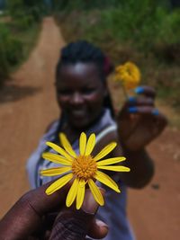 Cropped hand holding yellow flower by woman