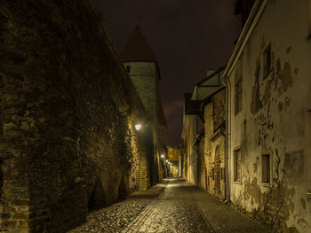 Alley amidst illuminated buildings at night