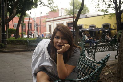 Portrait of woman sitting on sidewalk bench