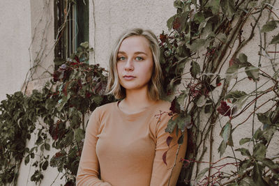 Portrait of beautiful young woman against plants