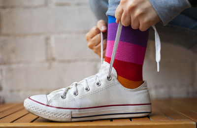 Woman tying laces of her white sneaker.