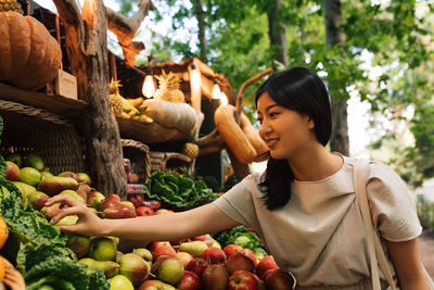 Portrait of young woman holding vegetables at market