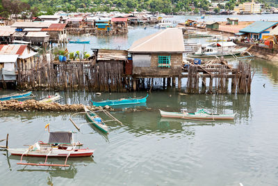 High angle view of fishing boats moored in river by buildings