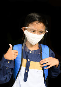 A young asian boy wearing masker and face shiled before going to school