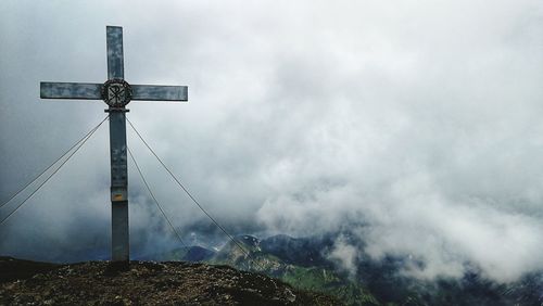 Low angle view of cross on mountain against sky