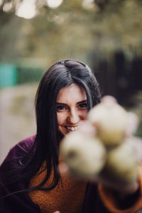 Young woman showing pears at the camera in the forest