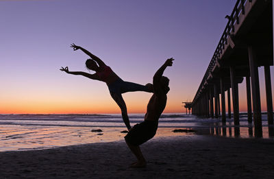 Silhouette people on beach against clear sky during sunset