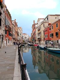 Canal amidst buildings in city against sky