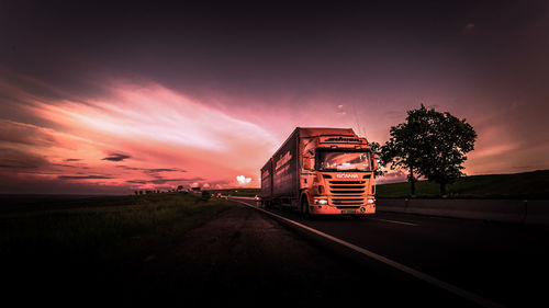 Railroad tracks by road against sky during sunset