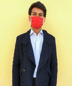 Portrait of young man standing against yellow wall