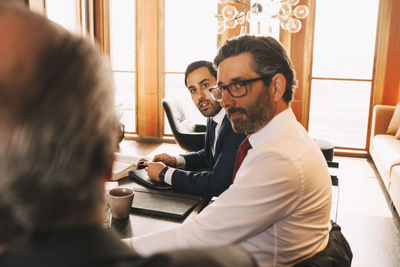 Male colleagues listening to mature lawyer during meeting at law office