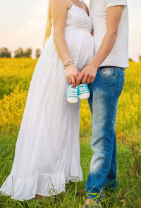 Midsection of man with pregnant wife holding baby booties