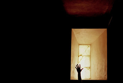 Close-up of a hand over a window on luminated lamp