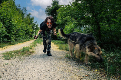 Cheerful young woman walking her dog on a leash. woman taking her dog for a walk