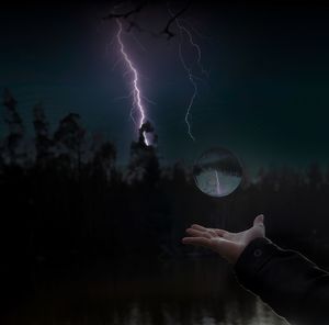 Low angle view of hands holding lightning at night