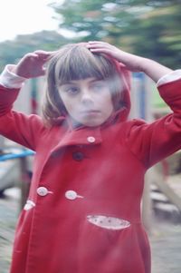 Portrait of girl with red arms outstretched standing outdoors