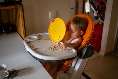 Toddler eating dirty in the highchair at home