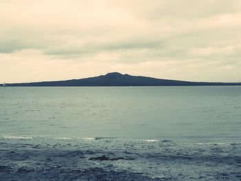 View of calm sea against mountain range