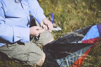 Midsection of man tying knot on kite