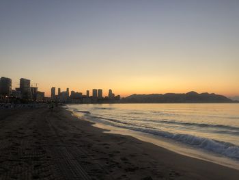 Scenic view of beach against clear sky during sunset