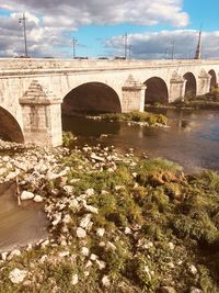 Arch bridge over river against sky