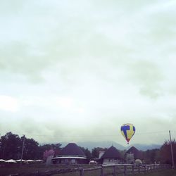 Hot air balloon flying over trees against sky