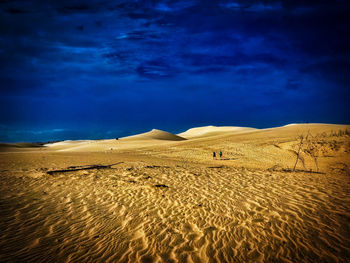 Sand dune in desert against blue sky