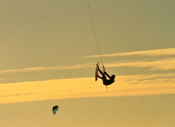 Person paragliding in sky during sunset