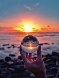 Midsection of person holding sun at beach during sunset