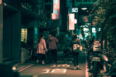 People walking on illuminated street in city