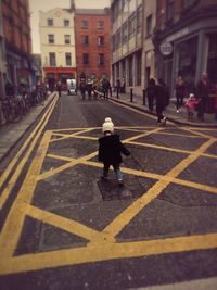 Rear view of woman walking on road in city