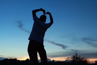 Rear view of silhouette man standing against sky during sunset